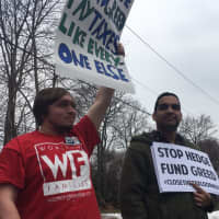 <p>Members of the Working Families Organization hold their signs in protest on Saturday, calling out hedge fund players for their greed.</p>