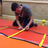 <p>Dumont sophomore Nicholas Chalarca sets up equipment in the gym during practice. He had to sit out because of a minor concussion.</p>