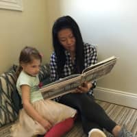 <p>Jinah Pacheco reads to a preschooler.</p>