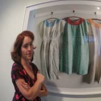 <p>ArtsWestchester Gallery Director Kathleen Reckling next to a photograph of mental hospital gowns, part of a display by Christopher Payne, on exhibit in White Plains, which reopens Jan. 3 through Jan. 14.</p>