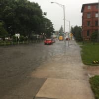 <p>All of Main Street in Danbury is flooded late Monday afternoon, with water flowing onto the sidewalk and up to the lawn near St. Peter&#x27;s School.</p>