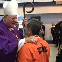 <p>Cardinal Dolan embraces a prisoner after the Mass service.</p>