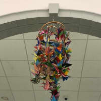<p>Paper cranes hang from the ceiling at the Wall Of Remembrance exhibit in Newtown.</p>