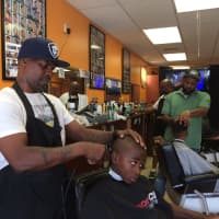 <p>Owner Harvey Robertson puts the finishing touches on a free haircut for 8-year-old Kiieer at North East Barbershop in Bridgeport.</p>