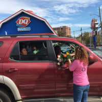 <p>Jasmine Rivera, manager at Stamford Florist, steps into the road to deliver free roses to a driver and passenger on Summer Street.</p>