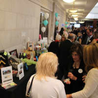 <p>Attendees appear near the silent auction table while placing their bids online. </p>