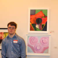 <p>Andrew Weatherly with two of his abstract paintings.</p>