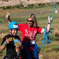<p>Ingrid Milne celebrates with a camper after a successful zipline run at a SeriousFun camp in Colorado.</p>