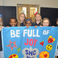 <p>Fifth-grade students at School of the Holy Child carry a banner they created for the Installation of the school&#x27;s new head of school, Melissa Dan.</p>