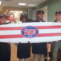 <p>The staff of Jersey Mike&#x27;s in East Rutherford proudly show off the surfboard that hangs in the shop as a  reminder of its Jersey shore origins.</p>