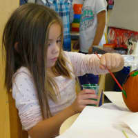 <p>A student paints a pumpkin as part of the fall festival.</p>