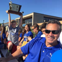 <p>Liam Johnson holds up the hardware behind NVD Athletics Director Greg Butler</p>