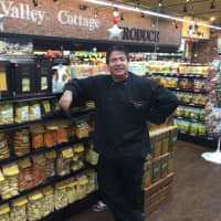 <p>Chef Marcello Russodivito in front of a display featuring his line of items.</p>