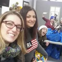 <p>Nikki Whitney (left) and her team pack personal items into bags to distribute to the homeless.</p>