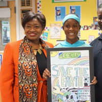<p>Olivia Moxey holding her winning Earth Day poster with her father and State Sen. Andrea Stewart-Cousins</p>