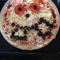 <p>My, what big black olive choppers you have! An example of a kid-made pie just before it was popped in the oven at Pizza One in Haskell.</p>
