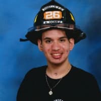 <p>Ariz Gomez proudly wears his helmet from the Theills Roseville Fire Department. The Garnerville teen was within months of becoming a probationary firefighter when he was felled by a massive stroke.</p>