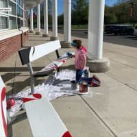 <p>A student paints a bench to show school spirit at Saxe Middle School.</p>