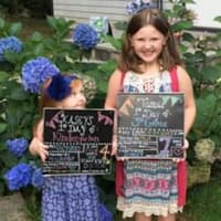<p>Little sister Kasey, who is headed for kindergarten, looks up to big sister Tara, a third-grader, on the first day of school in Danbury. </p>