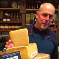 <p>Ken Skovron, co-owner of Darien Cheese &amp; Fine Foods, stands beside some of Montgomery’s cheddar from Somerset, England, that the company sells. It is recognized to be the benchmark of traditional cheddar cheesees.</p>
