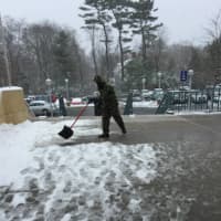 <p>A man at work cleaning snow and slush from Greenwich Library front entrance.</p>