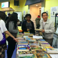 <p>Julio Reinoso, right, helps students pick from among the 1,500 free books available at the 2016 Bridgeport Youth Summit. Many were offered through the Friends of the Library.</p>