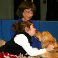 <p>Michele Meli looks on as a youngster meets a service dog.</p>