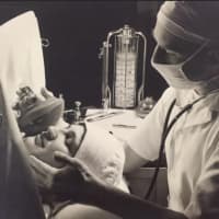 <p>A doctor tends to a patient in this 1938 image.</p>