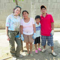 <p>Newtown resident Diane Sarna, posing with a family whose home she helped to build in Nicaragua.</p>