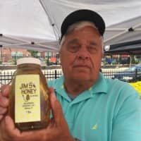 <p>Jim Johnson holds up a bottle of his his honey at the Danbury Farmers Market. The market opened Saturday and continues every Saturday until Oct. 22.</p>