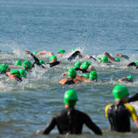 <p>A sea of swimmer in green caps and black wetsuits churn through the blue water in near ideal conditions at Saturday&#x27;s Swim Across America.</p>