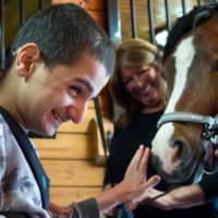 <p>A young boy with special needs pets a horse at Pony Power in Mahwah.</p>