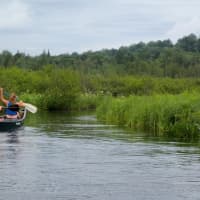 <p>Teenagers glide along Tupper Lake in a canoe as part of their activities in the Daniel Barden Scholarship Adventure.</p>