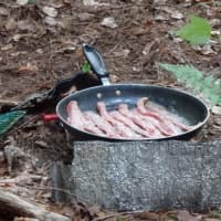 <p>Campers cook bacon for a meal in the Daniel Barden Scholarship Adventure.</p>