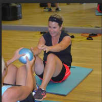<p>Feeling Fit client Tara Ackerly of Brookfield is doing partner sit-ups with a medicine ball pass.</p>