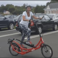 <p>Debi Povinelli, co-owner of the Ridgefield Running Company, riding the elliptiGO bicycle outside her store.</p>