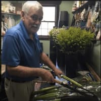 <p>Employee Bill Jack is processing and treating the flowers that just arrived. He is cutting them and putting them in water.</p>