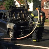 <p>A firefighter hoses off a charred SUV that went up in flames in Maywood Friday.</p>