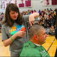 <p>Bethel High School senior Emma Fagan cuts the hair of her principal, Chris Troetti, as part of a fundraiser she organized to raise awareness and money for childhood cancer.</p>