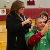 <p>Bethel High School principal Chris Troetti looks at his reflection after he got his head shaved at the event.</p>