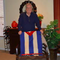 <p>Cuban native Celestino Heres in his Norwalk home.  He is holding the Cuban flag that his late mother made at the end of the Cuban Revolution.</p>