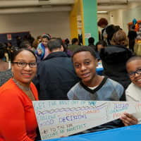 <p>Qadir Emile-Weekes, a ninth-grader from Saunders High School, shows off his &quot;vision&quot; banner while mom, Lorraine, and younger brother look on. The banners detail the students&#x27; goals for high school and college.</p>