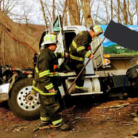 <p>Members of the Stepney Fire Department in Monroe work Monday to clean up an oil spill after an oil truck left the roadway on Judd Road at the Easton border.</p>