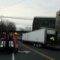 <p>Crews work to free the truck that was wedged under the Steamboat Road railroad bridge overpass Tuesday morning.</p>