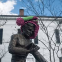 <p>Women dress one of the monuments outside the Bethel Library with a hat.</p>