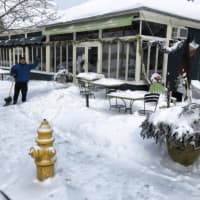 <p>An employee at Harborview Market keeps the sidewalk clear.</p>