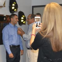 <p>Andrew Ponteciello receives his badge from his father as a family member snaps a few photos.</p>