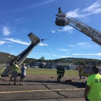 <p>Danbury firefighters help to put the plane back on its wheels after it landed on its nose at Danbury Airport on Friday morning.</p>