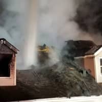 <p>Flames burn through the roof of a home on Fleetwood Drive in Danbury on Sunday evening.</p>