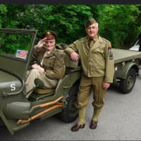 <p>A pair of veterans on a vintage World War II vehicle.</p>